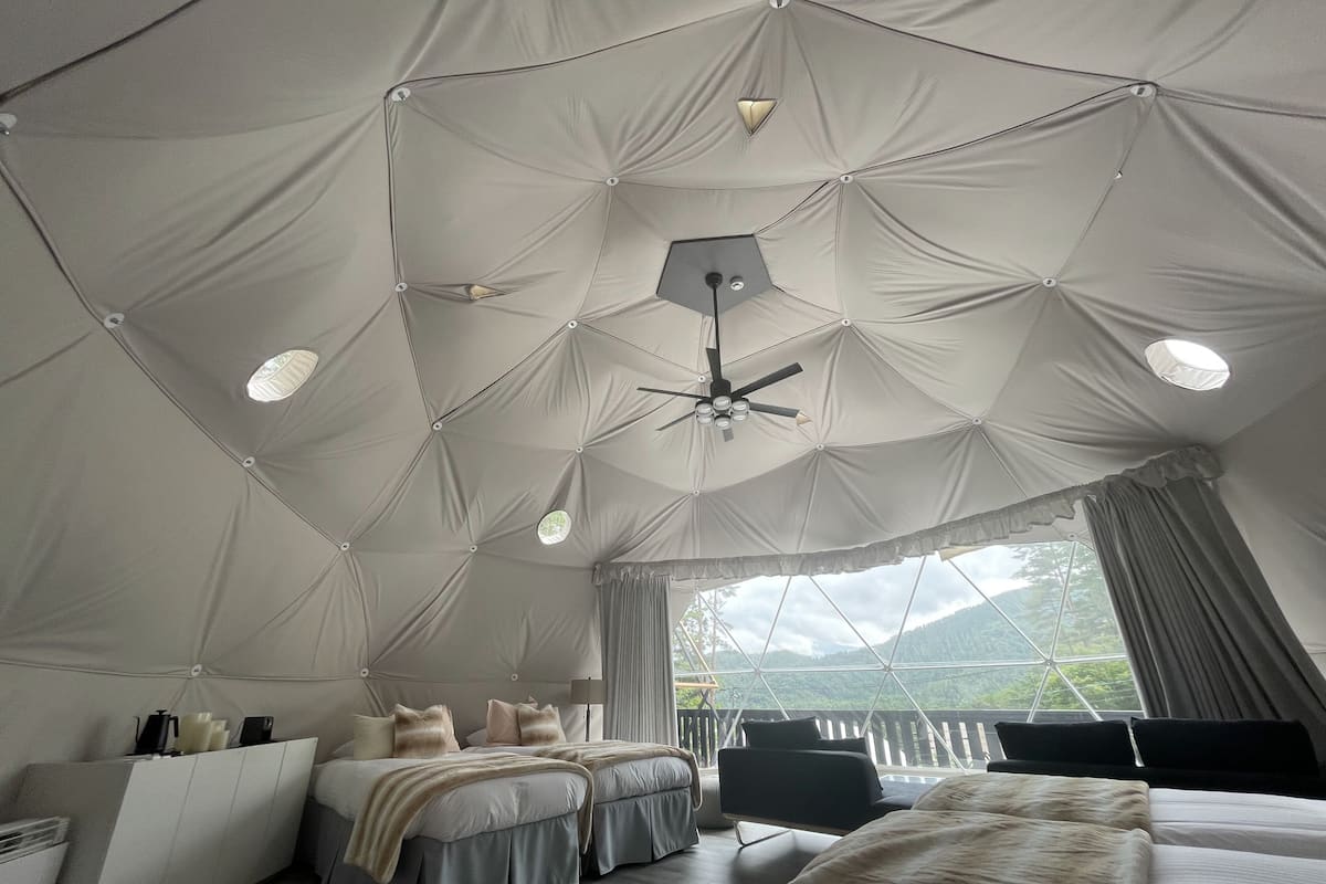 A tent-style room with two beds, a desk, and a chair.
