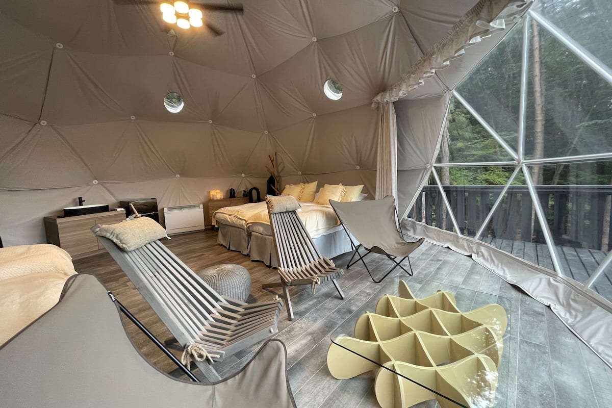 A tented accommodation with a bed, seating area, and a view of the outdoors.