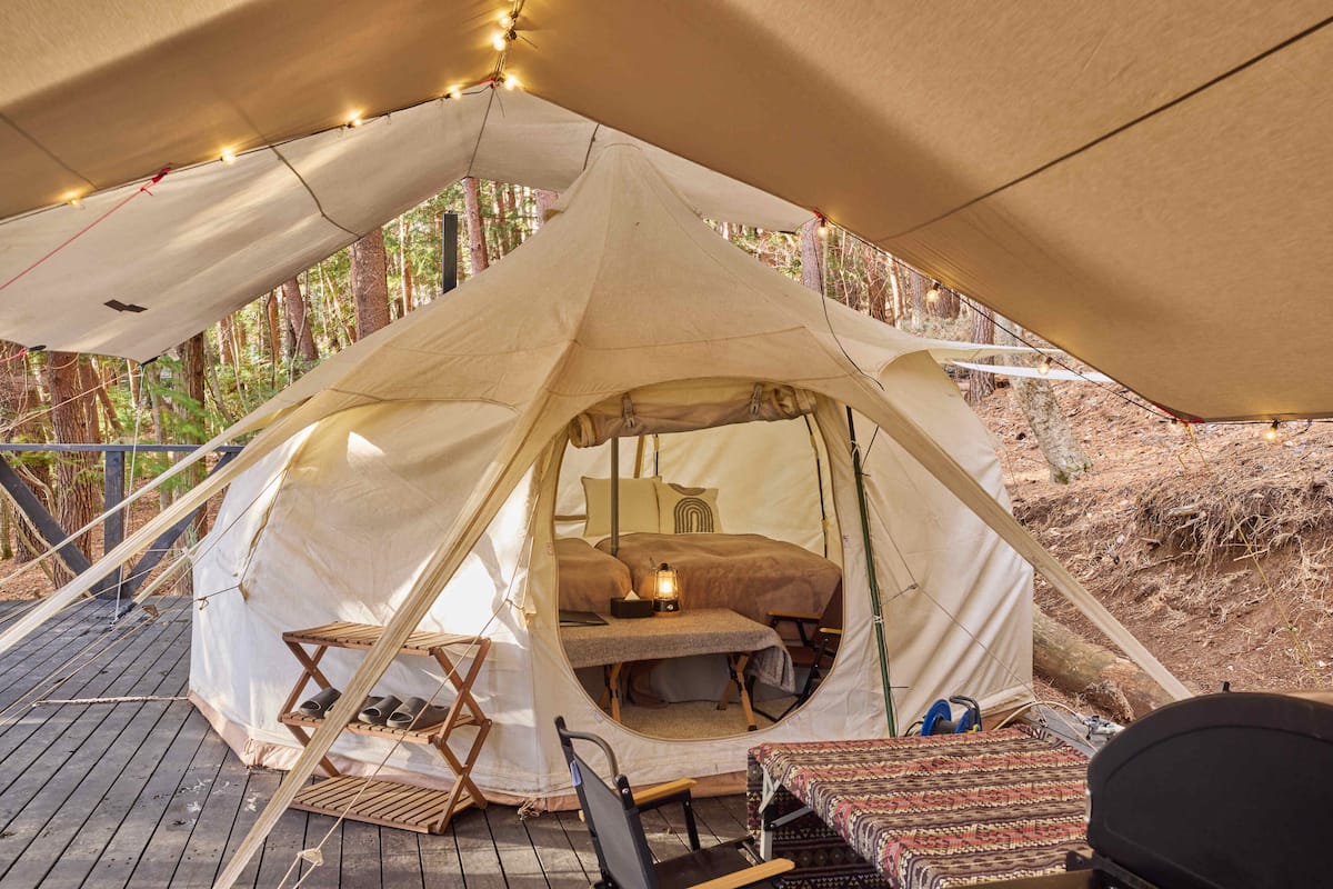 A tent with a bed, a small table, and a chair.
