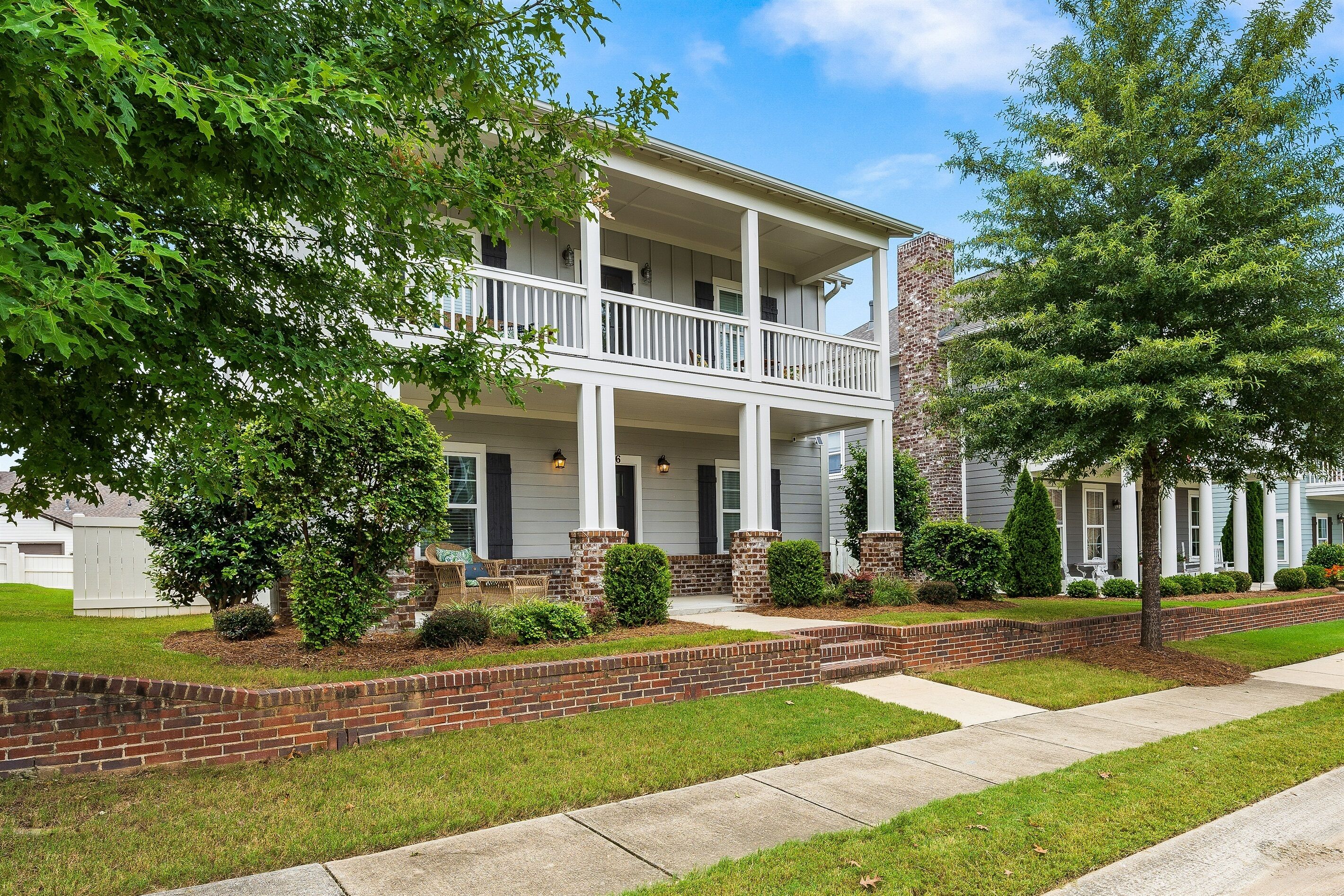 A two-story house with a front porch, brick foundation, and a well-maintained lawn.