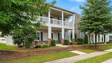 A two-story house with a front porch, brick foundation, and a well-maintained lawn.