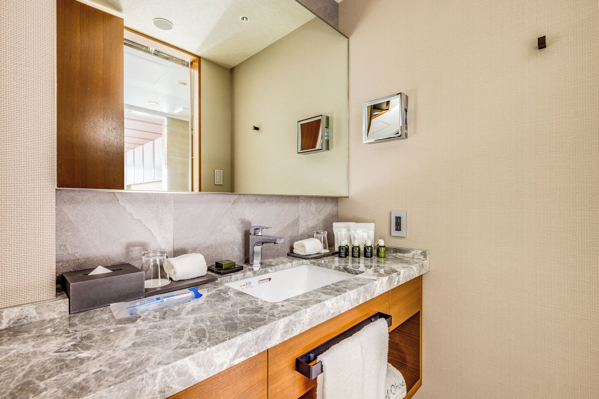 A bathroom with a marble sink, a mirror, a towel rack, and toiletries.