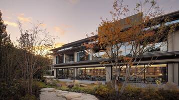 A modern building with a patio area, outdoor seating, and a garden with rocks and trees.
