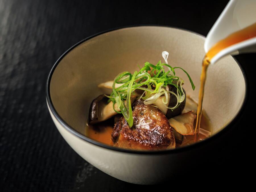 A bowl of food with a liquid being poured into it.