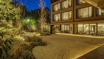 A modern building with a landscaped garden area featuring a patterned gravel path and various plants.