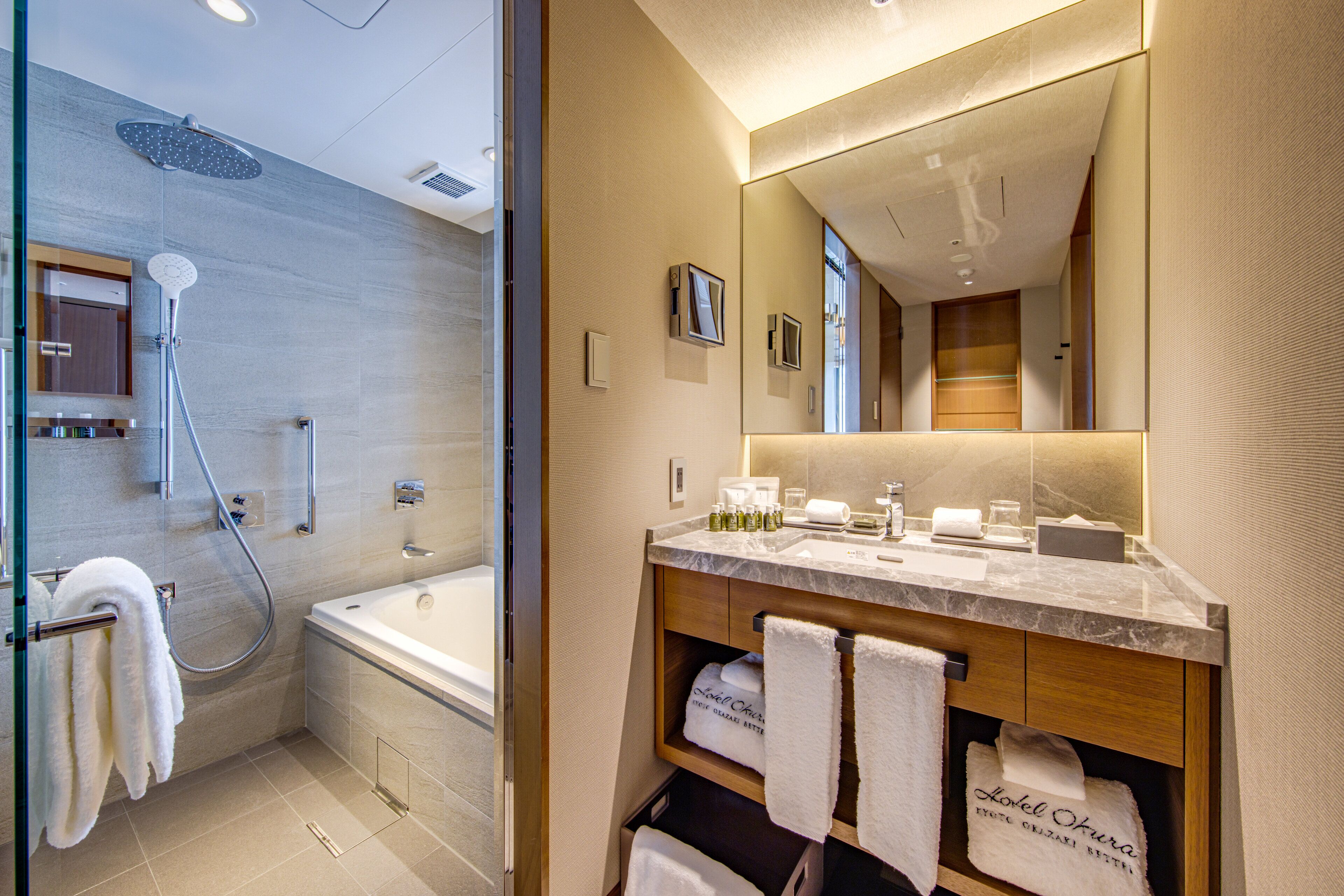 Une salle de bain moderne avec une douche à parois de verre, un grand miroir et un comptoir en marbre.