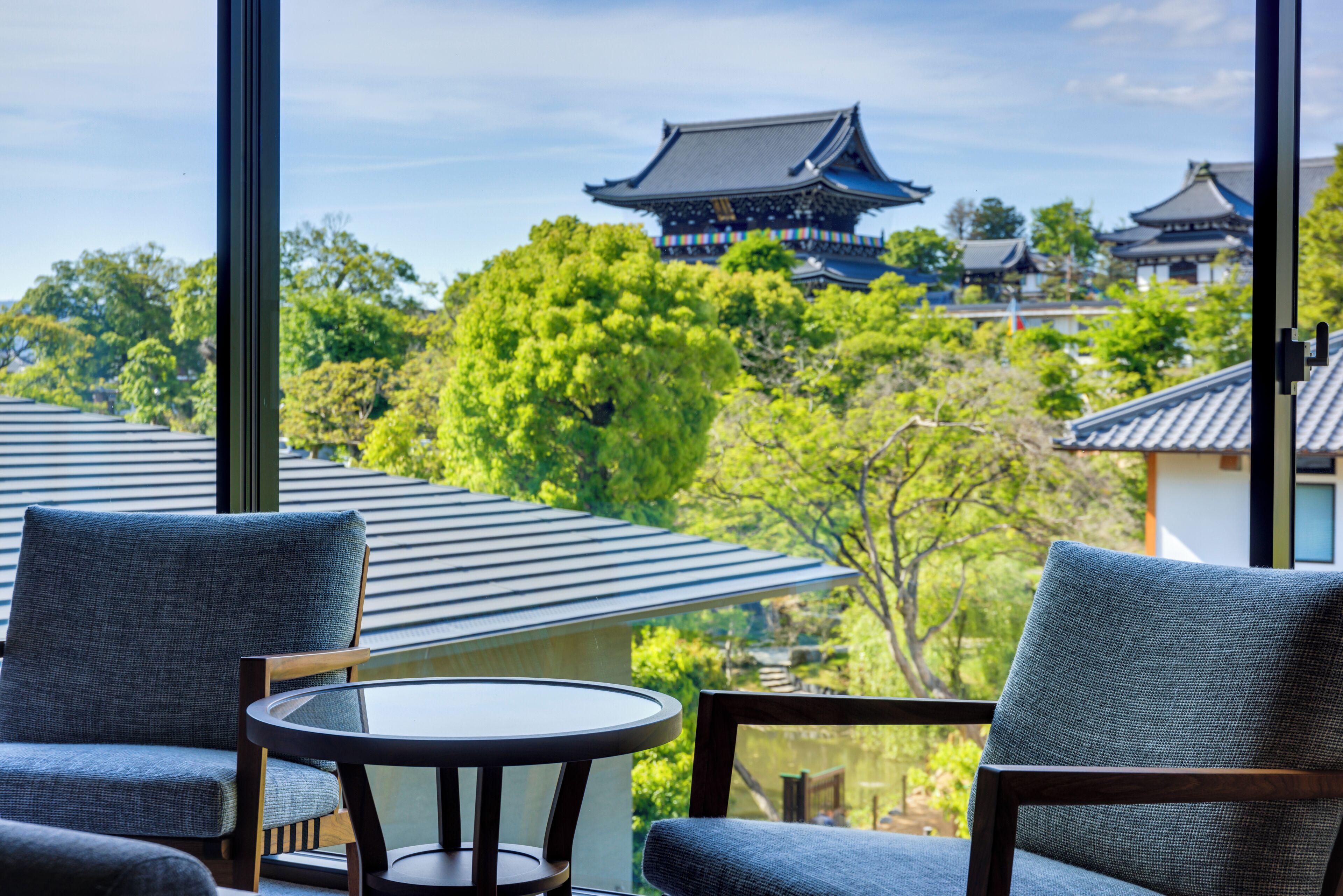 A traditional Japanese-style room with tatami mats, a low table, and a view of a temple in the background.