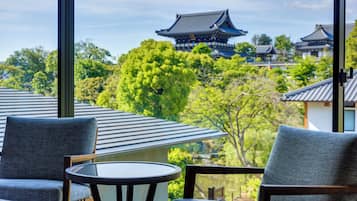 A traditional Japanese-style room with tatami mats, a low table, and a view of a temple in the background.