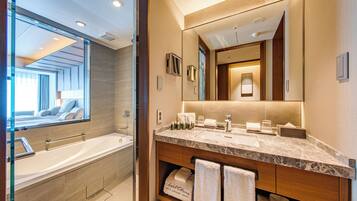 A modern bathroom with a large mirror, a bathtub, and a marble countertop.