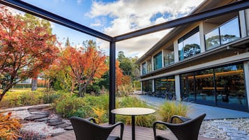 Une terrasse extérieure avec une table et des chaises, entourée d’un jardin aux couleurs automnales.