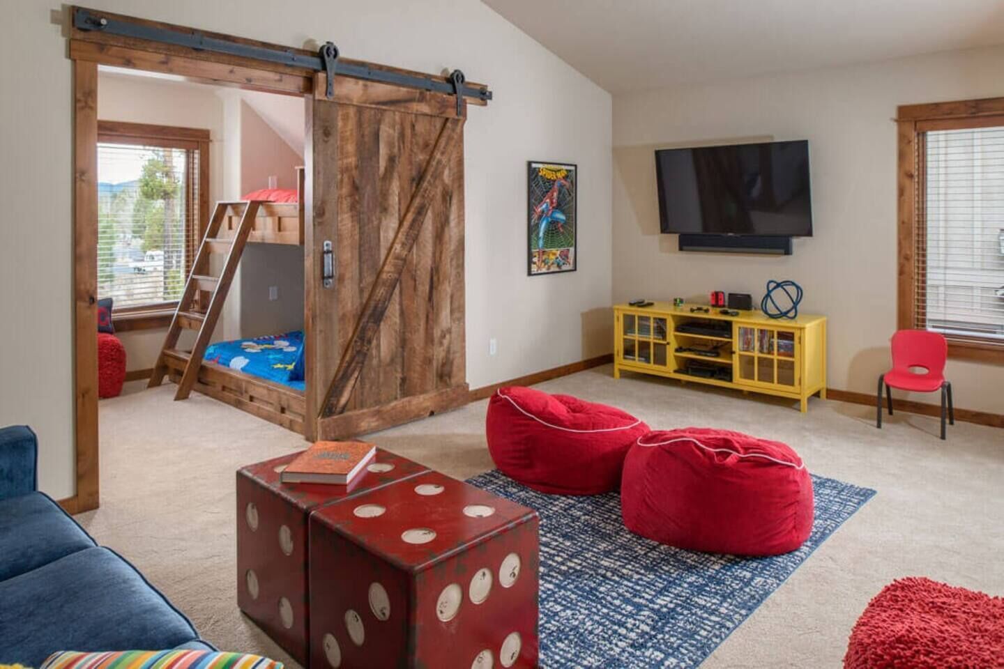 A cozy living room with a loft bed, a TV, a yellow cabinet, and red bean bags.