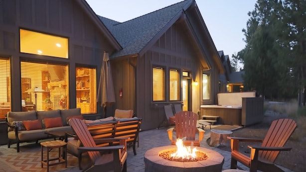 Un espacio al aire libre acogedor con una chimenea, mobiliario de madera y ventanas amplias.