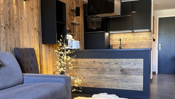 A modern living room with a grey sofa, a wooden accent wall, and a small white rug. - Stunning 8-person apartment, central location, pets allowed (Avoriaz)