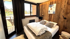 A bedroom with a bed, a window, a wooden wall, and a view of the outside. - Stunning 8-person apartment, central location, pets allowed (Avoriaz)