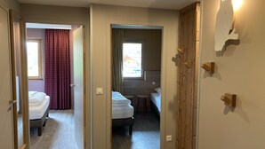 A hotel room with a bed, a small stool, a window with curtains, and a wooden wardrobe. - Comfortable apartment 7 people, ski-in, Avoriaz (Avoriaz)