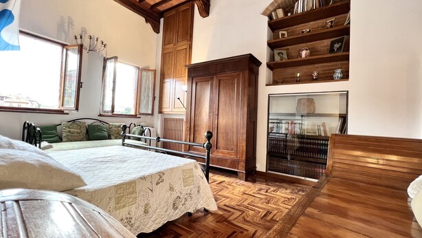 A room with a bed, a wooden cabinet, a bookshelf, and a window. - Duprè Apartment (Siena)