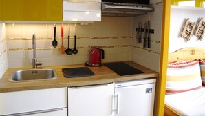 A compact kitchen with a sink, a microwave, and a stove. There are utensils hanging on the wall and a small refrigerator. - Renovated studio with south-facing balcony in Avoriaz (Avoriaz)