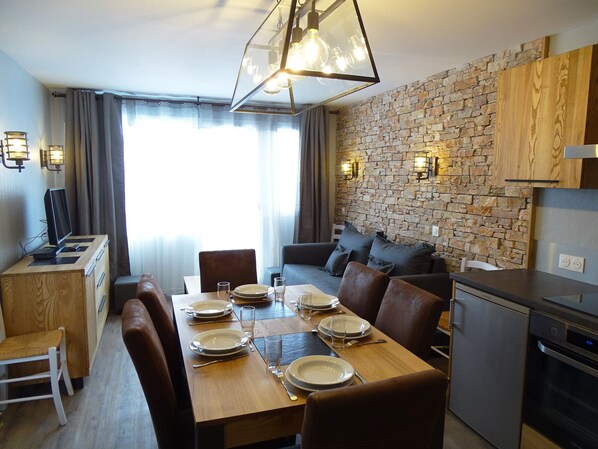 Een moderne keuken met een backsplash van natuursteen, houten keukenkastjes en een eethoek met een tafel gedekt voor vier personen.