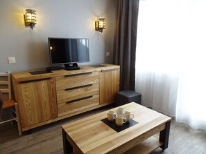 A modern room with a wooden cabinet, a flat-screen TV, and a coffee table with cups.