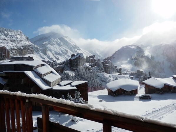 A snowy mountain village with wooden buildings and a clear view of the surrounding mountains.