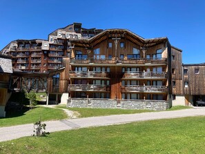 Un hotel de varios pisos con balcones, cimientos de piedra y un cielo despejado.