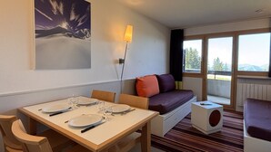 Una habitación moderna con una mesa de comedor preparada, un sofá y una ventana con vistas.