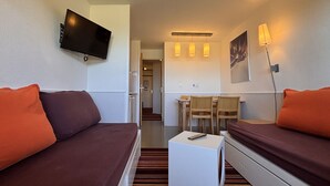 Habitación de hotel con dos camas, un televisor, un escritorio con sillas y una lámpara.