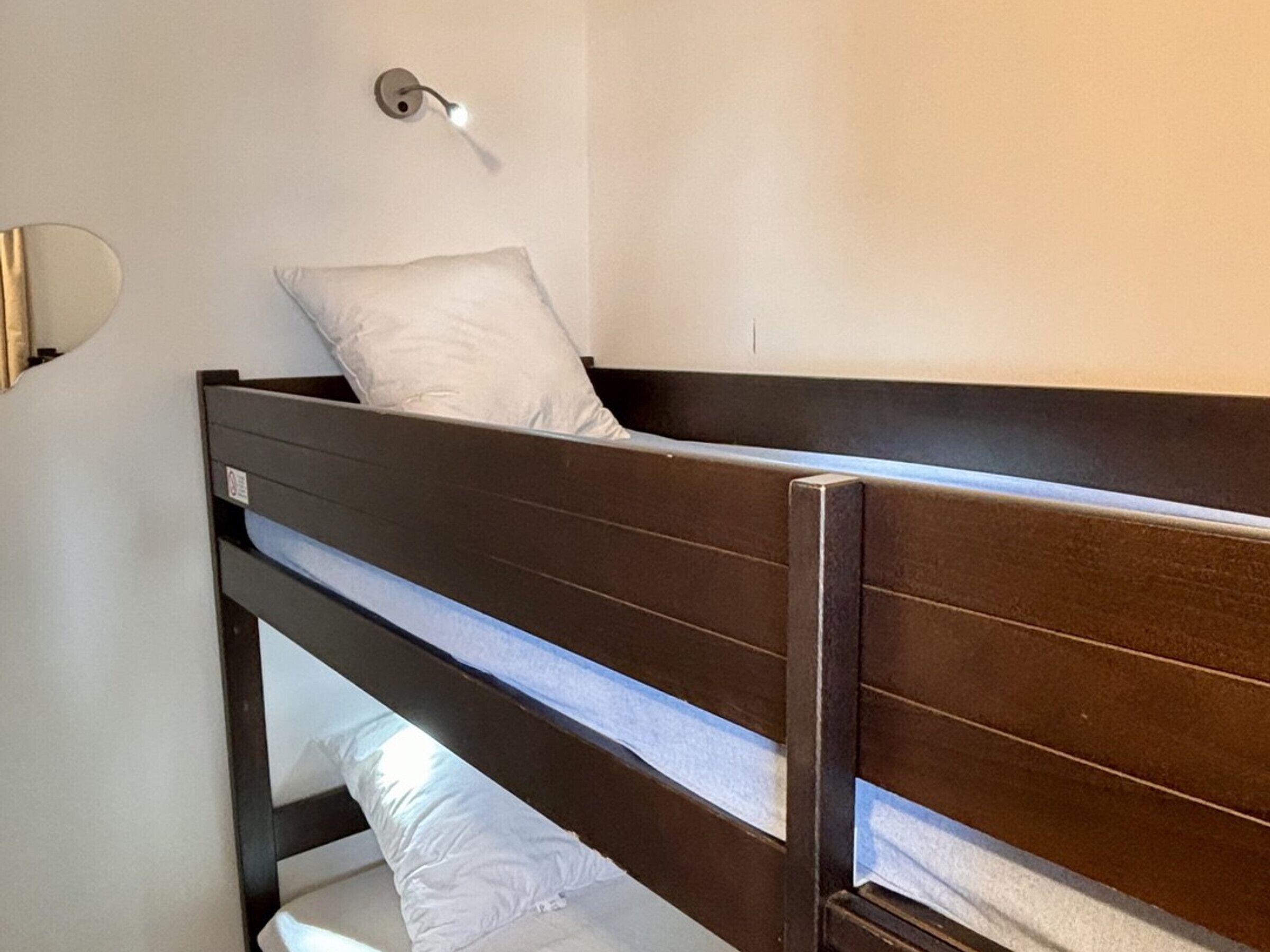 A bunk bed with a wooden frame and white bedding.