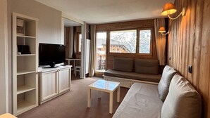 En hyggelig stue med sofa, fjernsyn og trævægge.