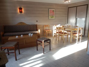 Un salon confortable avec un canapé, une table basse et une table à manger pour quatre personnes.