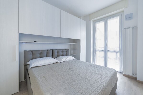 A bedroom with a bed, built-in wardrobe, and a window with a view.