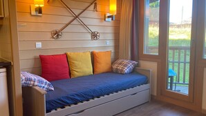 A cozy room with a bed, wooden walls, and a window with a view of the outdoors.