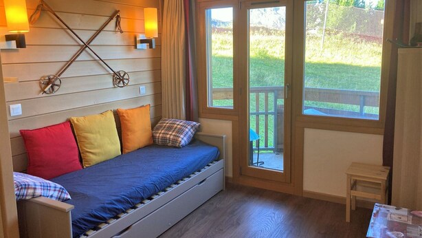 A cozy room with a bed, a small table, and a window with a view of a garden.