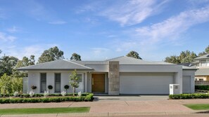 A modern two-story house with a garage, a well-maintained front yard, and a clear blue sky. - HUNTER VALLEY WILDFLOWER (POKOLBIN)