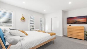 A bedroom with a bed, a dresser, a wall-mounted painting, and a window with blinds. - HUNTER VALLEY WILDFLOWER (POKOLBIN)