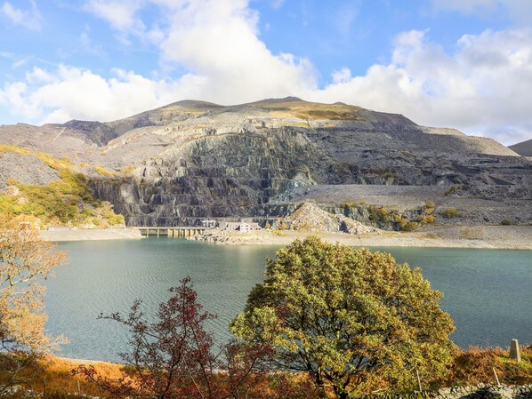 Un paisaje montañoso con un lago, un puente y un conjunto de edificios.