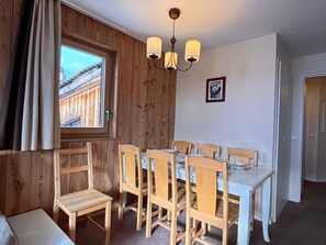 A dining area with wooden walls, a window, and a chandelier.