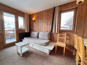 A cozy room with a wooden wall, a sofa, a small table, and two chairs.