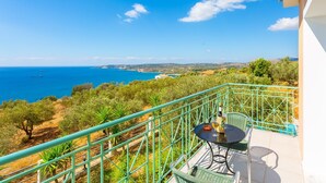 A balcony with a table and chairs overlooking a coastal view. - Villa Eri in Vlachata (Kefalonia)