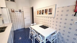 A kitchen with a white table and chairs, a stove, and a tiled backsplash with pictures. - Comfort and quiet in Lisbon center (Lisboa)