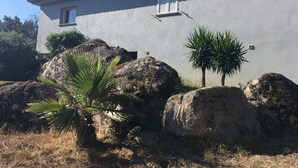 Una casa con esterno grigio, persiane bianche e una piccola finestra.