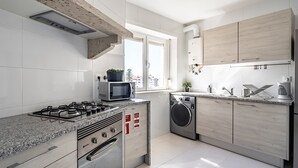 Eine moderne Küche mit Gasherd, Mikrowelle, Backofen und Waschmaschine.