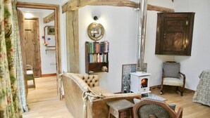 A cozy living room with a wooden sofa, a fireplace, a bookshelf, and a chair.