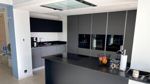 Een moderne keuken met een centraal eiland, inbouwapparatuur en een glazen dak.