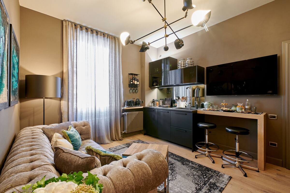 Un saló modern amb un sofà, una taula de centre i una televisió. Hi ha una zona de cuina amb una barra i tamborets.