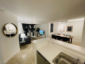 Relax in this stylish living room with a flat-screen TV, dining table, and comfortable seating for four.