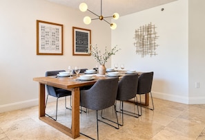 A dining area with a wooden table, grey chairs, and a vase with branches. - LUXURY THE YATCH 402- FREE PARKING AND WIFI (Aventura)
