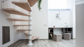 Un interior moderno con una escalera espiral, una estantería y un pequeño rincón de descanso.