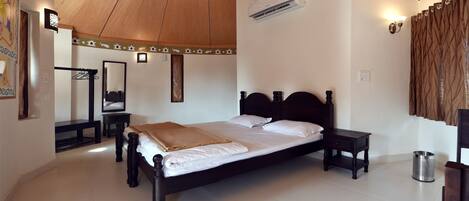 A neatly arranged bedroom with a large bed, a bedside table, a hanging light, and a ceiling fan.