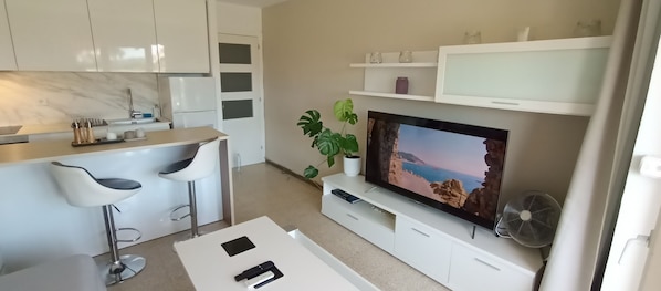 A modern kitchen with white cabinets, a marble countertop, and two bar stools.